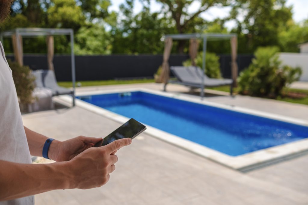 man has smart system installed for pool and is using phone - Puravida, New Jersey 